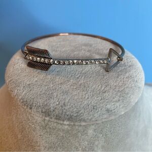 Hinged silver tone bangle bracelet with feathered arrow and clear glass